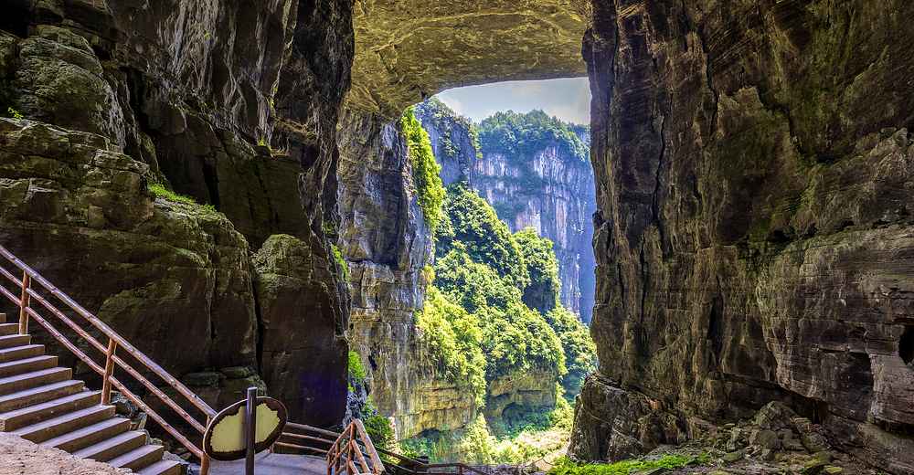 The majestic Wulong Tiankeng (Three Natural Bridges) with towering limestone formations surrounded by lush greenery, showcasing Chongqing's stunning natural landscapes.