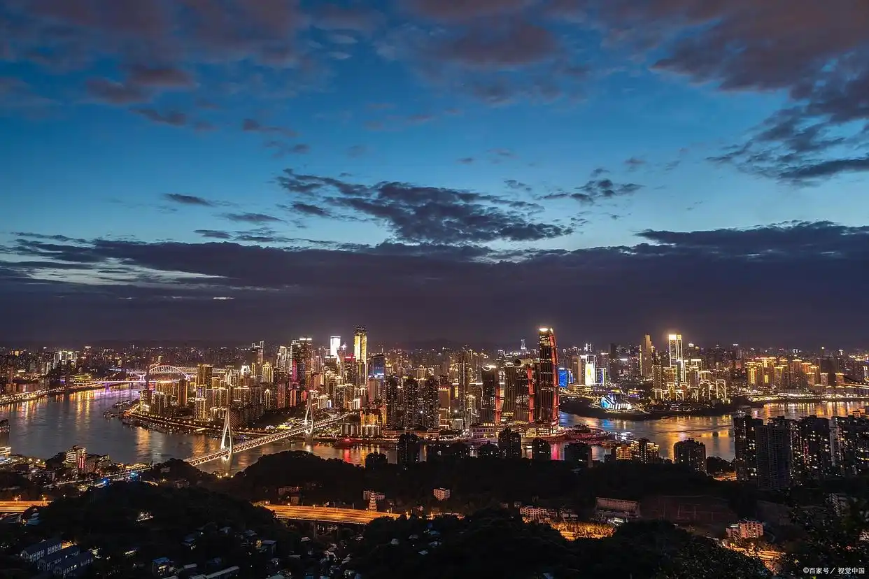 A panoramic night view of Chongqing's layered cityscape with skyscrapers, bridges, and mountains illuminated against the dark sky, capturing the city's magical atmosphere.